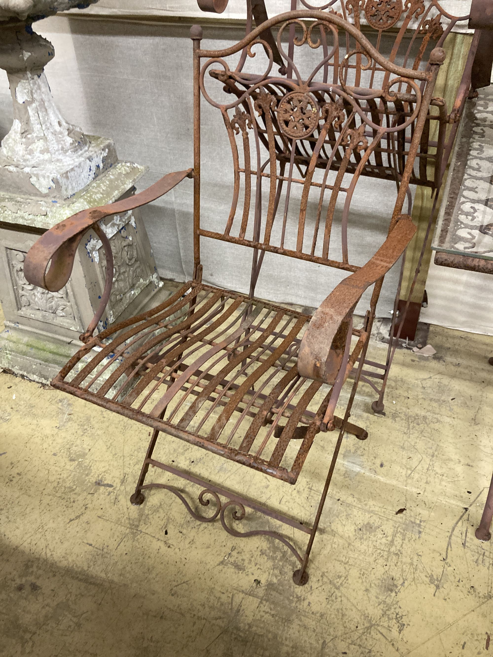 A wrought iron garden table, width 160cm, depth 80cm, height 76cm and six folding chairs